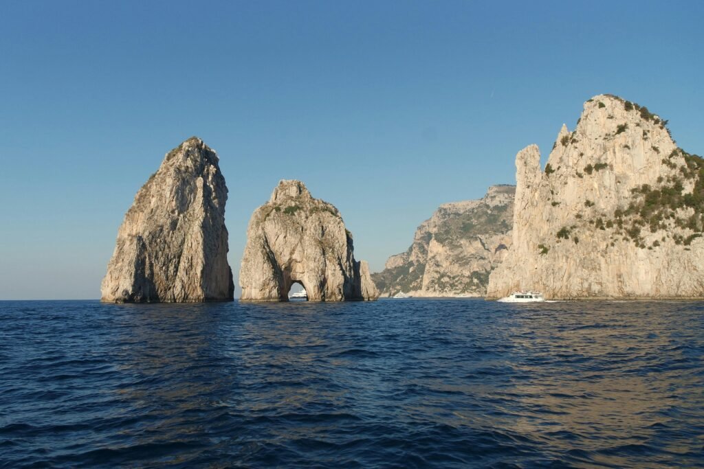 Stunning view of the Faraglioni rock formations off the coast of Capri, Italy, under a clear blue sky.