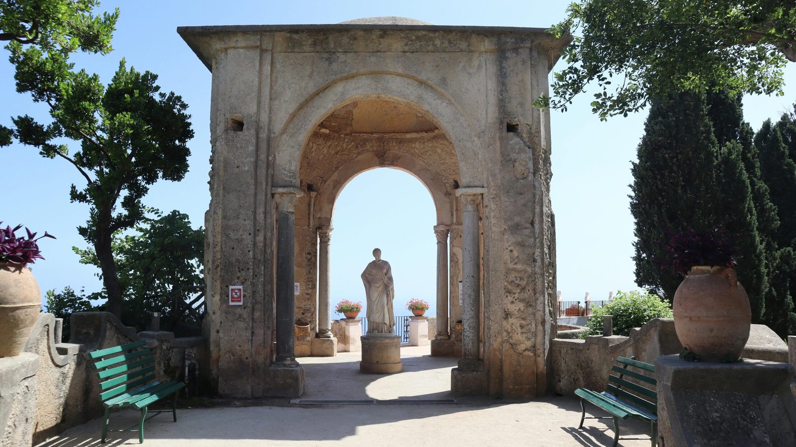 Historic garden in Ravello with a stunning stone arch and statue.